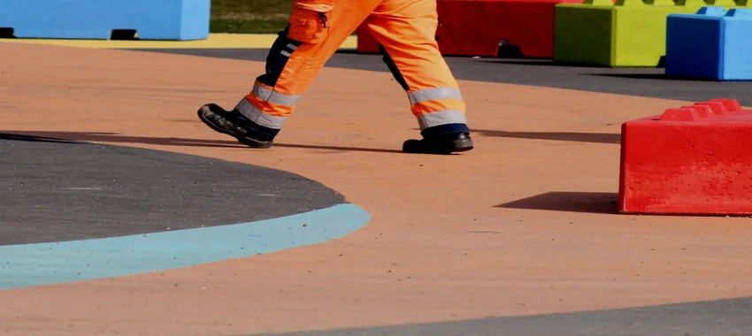 Worker wearing safety boots walking on a paved surface in high-visibility workwear