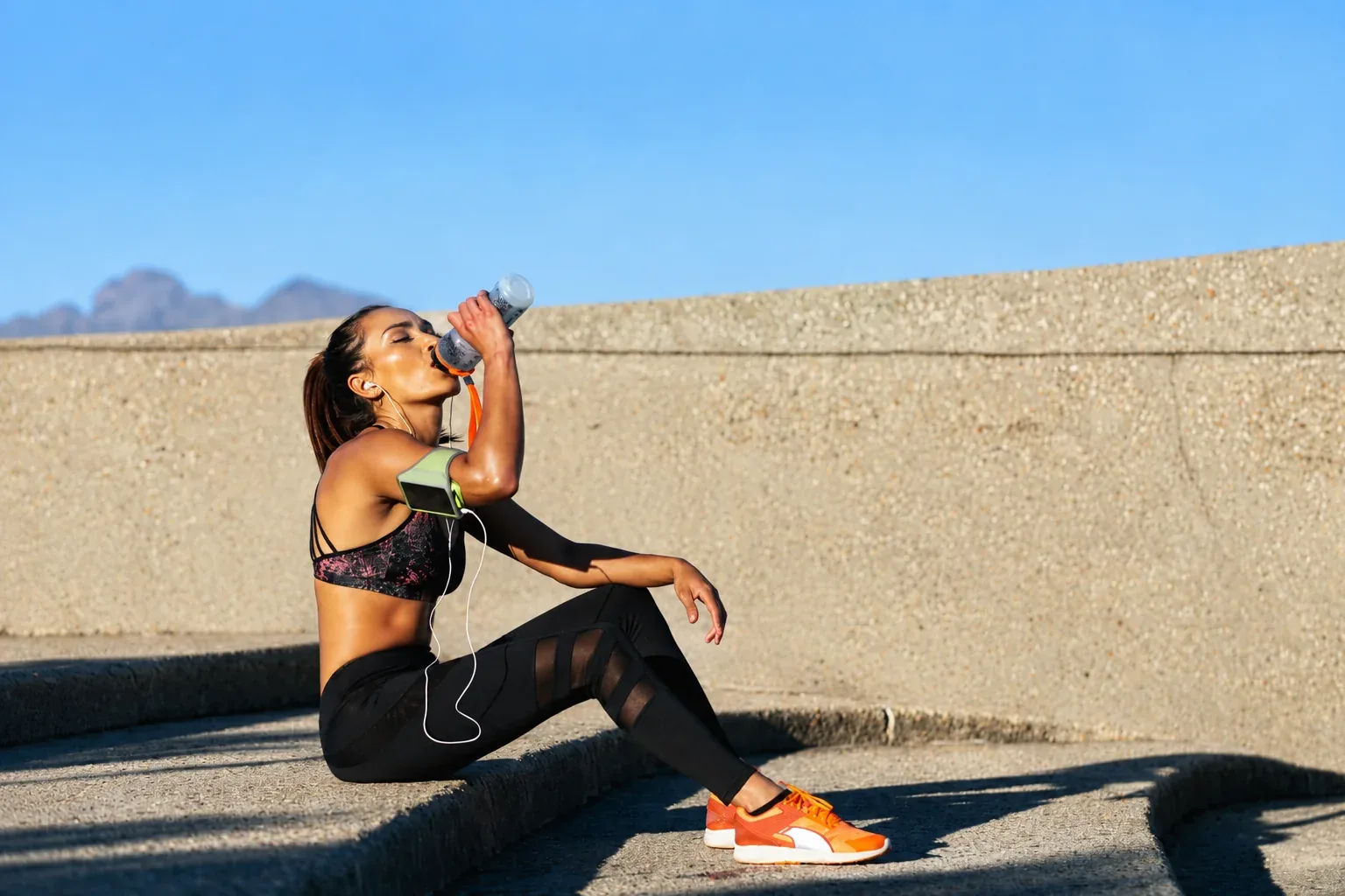 Woman drinking water while resting after an outdoor workout